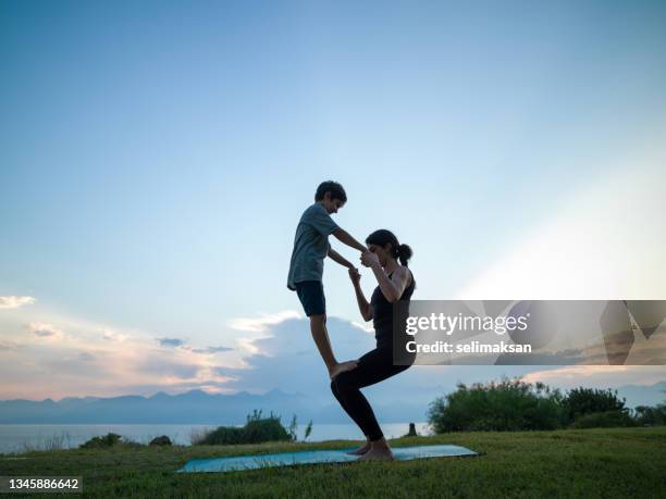 photo of adult woman and 8 years old boy during yoga exercises in sunset - 8 9 years 個照片及圖片檔