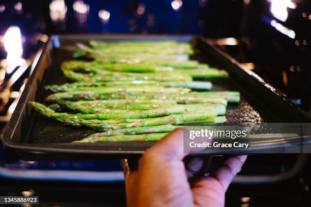 woman places asparagus in oven - cooked asparagus stock pictures, royalty-free photos & images