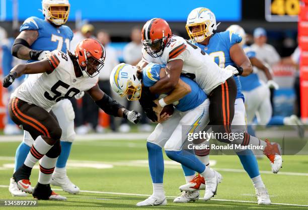 Justin Herbert of the Los Angeles Chargers is sacked by Myles Garrett and Malik McDowell of the Cleveland Browns during the third quarter at SoFi...