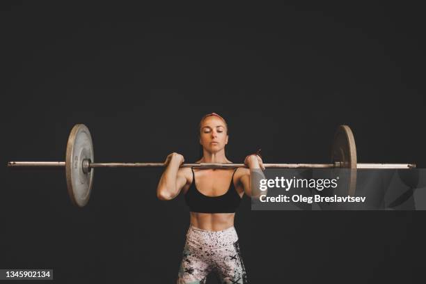 woman weightlifting. portrait of strong girl holding barbell - sollevamento pesi femminile foto e immagini stock