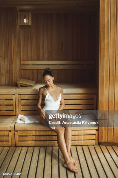 young beautiful multiracial woman making anti cellulite or lymphatic dry massage at  finnish sauna. - natural organic thermo cosmetics stock-fotos und bilder