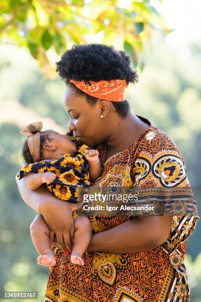 afro mother kissing baby outdoors - brazil village stock pictures, royalty-free photos & images