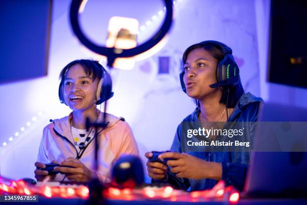 two young black female gamers playing at night - videospel stockfoto's en -beelden