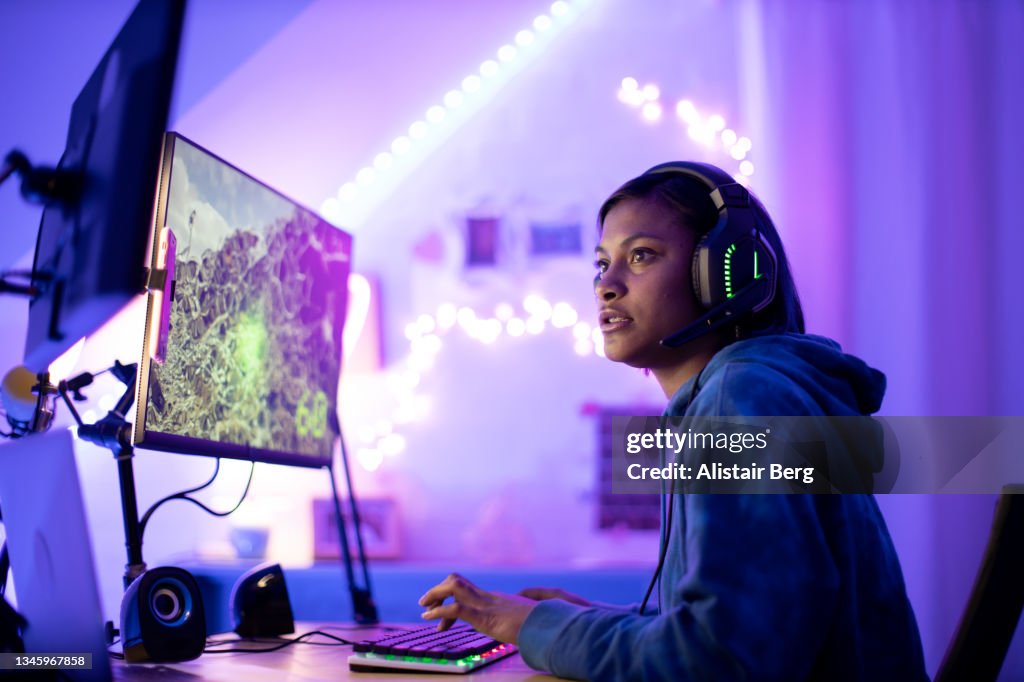 Young black female gamer playing at night