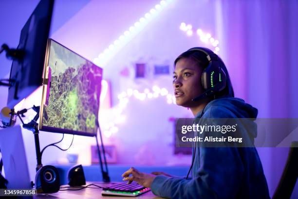 young black female gamer playing at night - video game stock-fotos und bilder