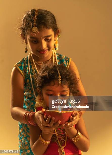 two young indian girl holding diwali oil lamp - diya oil lamp stockfoto's en -beelden