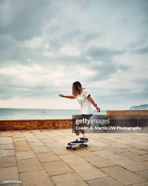 young sporty woman riding on skateboard on the road - longboard skating stock pictures, royalty-free photos & images