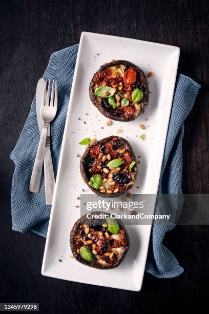 filled portobello mushrooms with sun dried tomatoes and mozzarella cheese. - portobello mushroom stock pictures, royalty-free photos & images