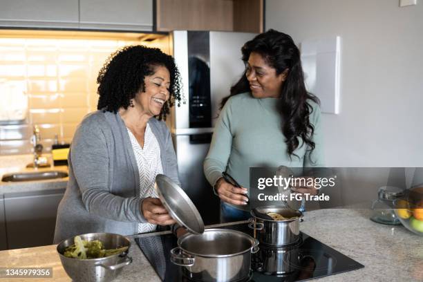 mother and daughter cooking at home - stove top stock pictures, royalty-free photos & images