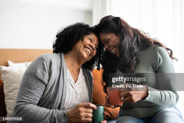 bonding moment between mother and daughter at home - black female friends stockfoto's en -beelden