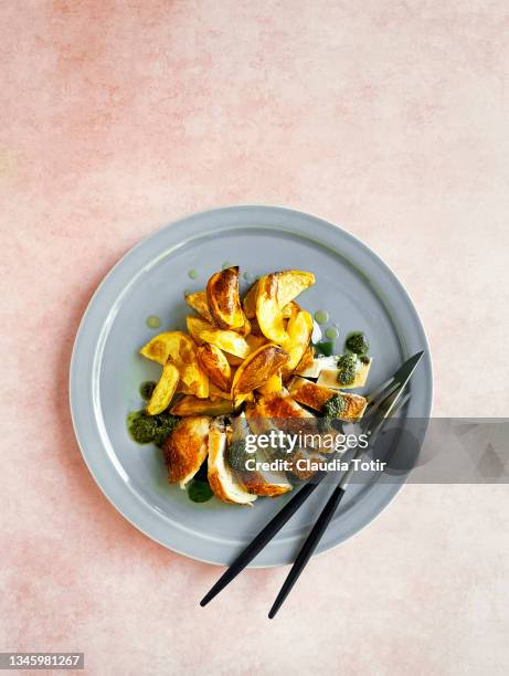 a plate of roasted potatoes with sliced chicken breast on peach background - gegrillte hühnerbrust stock-fotos und bilder
