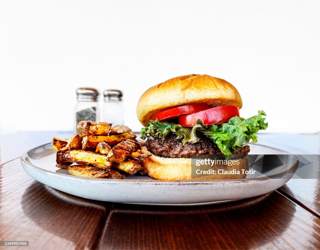 Burger with French fries on a plate on white background