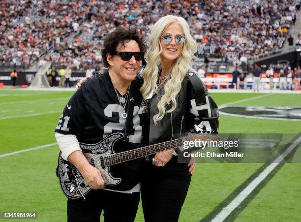 Recording artist Neal Schon of the band Journey and his wife, television personality Michaele Schon, pose on the field before Neal Schon performs the...