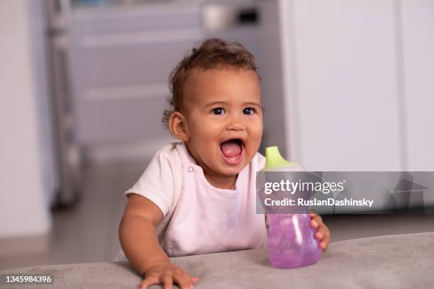 baby with water bottle. - african girl drinking water stockfoto's en -beelden