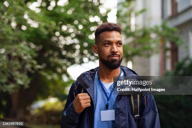 man caregiver, male nurse or healthcare worker outdoors on the way to work. - doctor uniform stockfoto's en -beelden