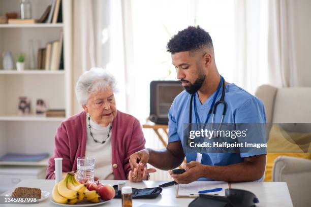 young healthcare worker doing blood sugar test to diabetic senior woman indoors at home - diabetes testing stock pictures, royalty-free photos & images