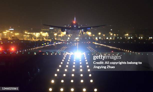 aircraft landing in front of runway lights of airport late at midnight - runway night stock pictures, royalty-free photos & images