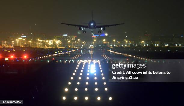aircraft landing in front of runway lights of airport late at midnight - runway night stock pictures, royalty-free photos & images
