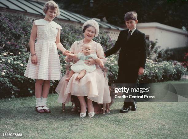 Queen Elizabeth, the Queen Mother sits with her grandchildren Prince Charles, Princess Anne and baby Prince Andrew, the children of Queen Elizabeth...