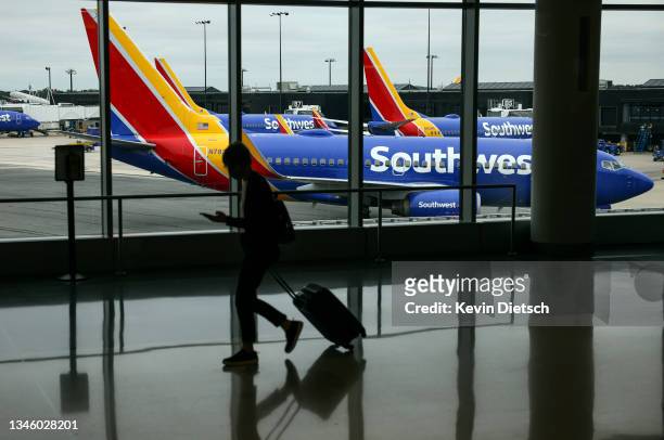 Traveler walks past a Southwest Airlines airplane as it taxies from a gate at Baltimore Washington International Thurgood Marshall Airport on October...