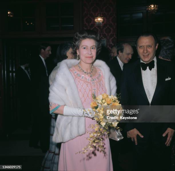 Queen Elizabeth II wearing a pink beaded evening gown and a white fur stole, circa 1975.