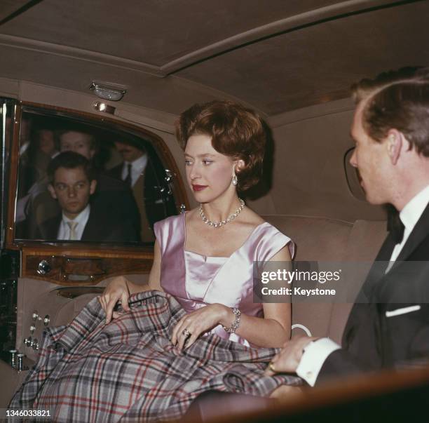 Princess Margaret and her husband Lord Snowdon keep warm with a rug in the back seat of a car, circa 1962.