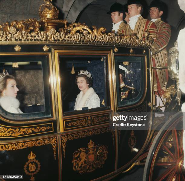 Queen Elizabeth II and Princess Anne attend the State Opening of Parliament in London, circa 1971. The Queen is wearing a full length fur-trimmed...