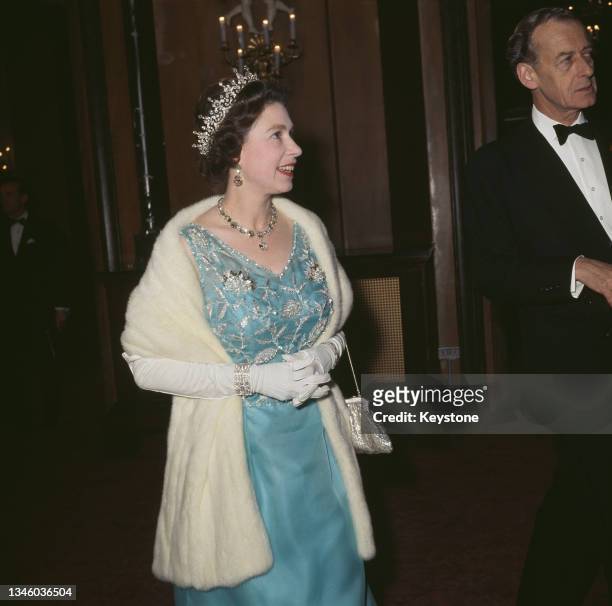 Queen Elizabeth II wearing an embroidered blue evening gown with a white fur stole, circa 1970.