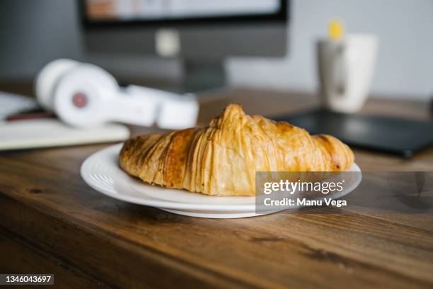 close up of crispy fresh croissant arranged on wood table and headphones on workplace table on daytime - plate side view stock pictures, royalty-free photos & images