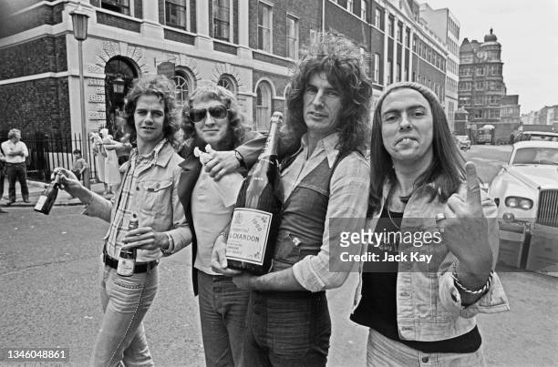 English rock group Slade celebrate with champagne outside the offices of Polydor Records on Stratford Place in London, after their single 'Skweeze...
