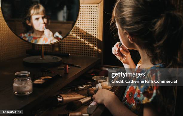 a little girl applies lipstick - girl in mirror stockfoto's en -beelden