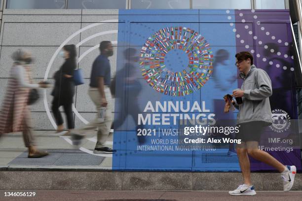 Man passes by a poster of the annual World Bank Group and International Monetary Fund meetings October 11, 2021 in Washington, DC. The annual...