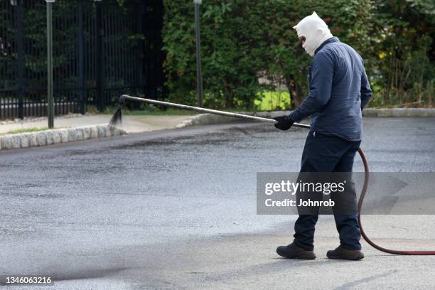 workman spraying asphalt sealcoating - driveway sealant stock pictures, royalty-free photos & images