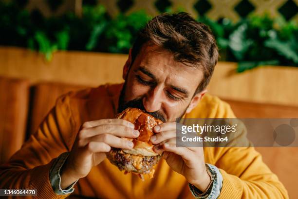 ich genieße jetzt meinen lieblings-cheeseburger - adults eating hamburgers stock-fotos und bilder