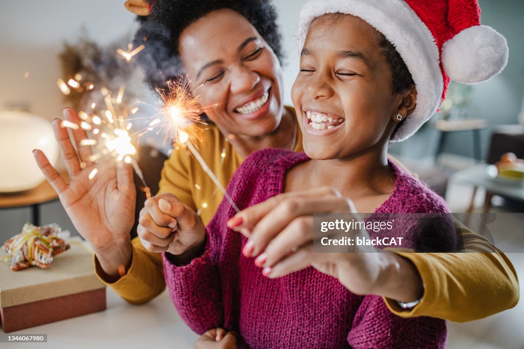 Portrait of a mother and daughter holding New Year's sparklers at home