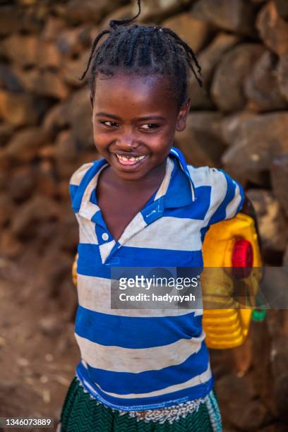 afrikanisches mädchen, das wasser aus dem brunnen trägt, äthiopien, afrika - traditional ethiopian girls stock-fotos und bilder