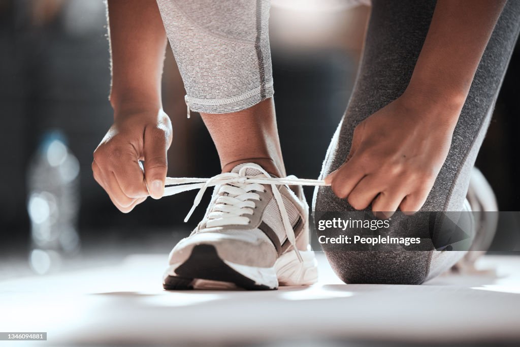 Photo recadrée d’une femme méconnaissable attachant ses lacets alors qu’elle faisait de l’exercice au gymnase