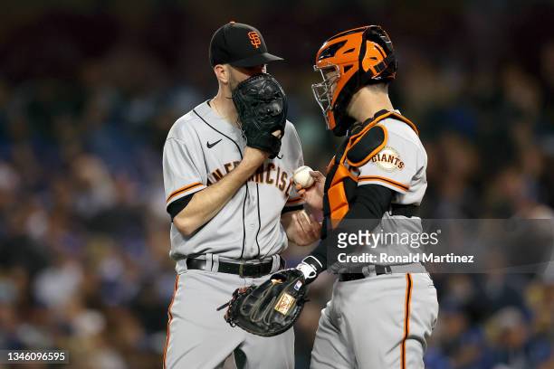 Alex Wood and Buster Posey of the San Francisco Giants meet at the pitchers mound against the Los Angeles Dodgers during the third inning in game 3...