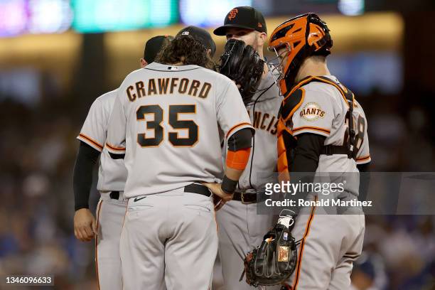 Alex Wood, Brandon Crawford and Buster Posey of the San Francisco Giants meet at the pitchers mound against the Los Angeles Dodgers during the third...