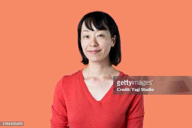 portrait of japanese mature woman on orange background - kinki stockfoto's en -beelden