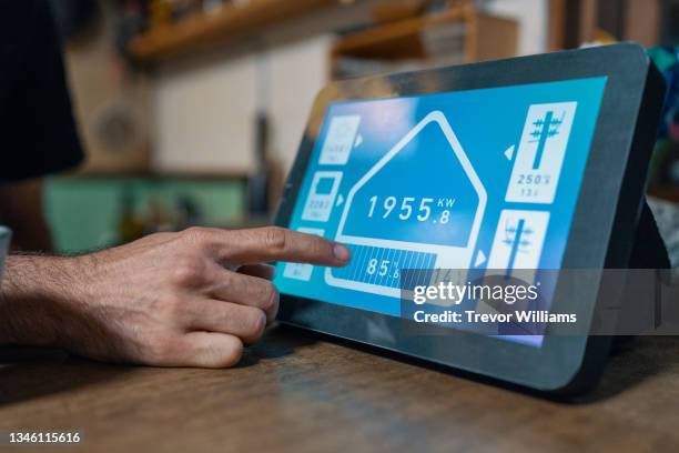 mid adult man checks electricity consumption for his home with a smart device - connected home stock-fotos und bilder