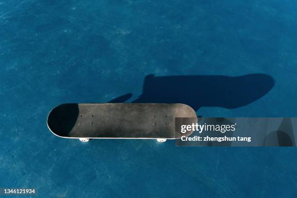 black skateboard isolated on blue ground of playground - skateboard bildbanksfoton och bilder