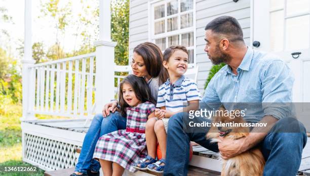 famille heureuse avec deux petits enfants et un chien de compagnie assis sur les marches du porche - loggia photos et images de collection