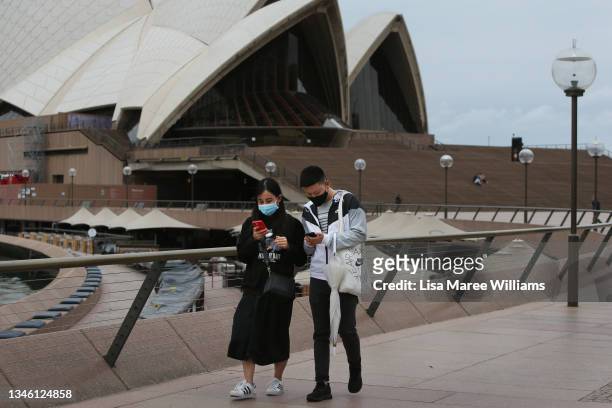 People walk along the Sydney Opera House concourse on October 12, 2021 in Sydney, Australia. COVID-19 restrictions eased across NSW as of Monday...