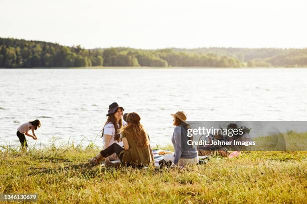 women having picnic at lake - summer picnic stockfoto's en -beelden