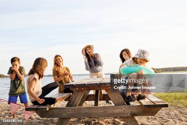family having picnic at lake - garden table stock-fotos und bilder