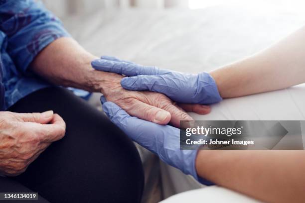 nurse holding woman's hand - senior care stock pictures, royalty-free photos & images