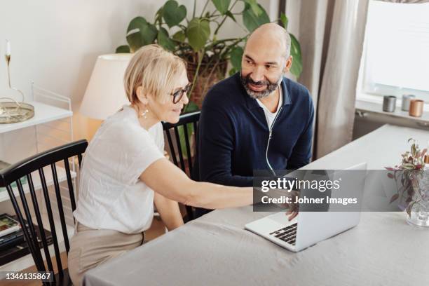 couple using laptop at home - couple 50 55 laptop stock-fotos und bilder