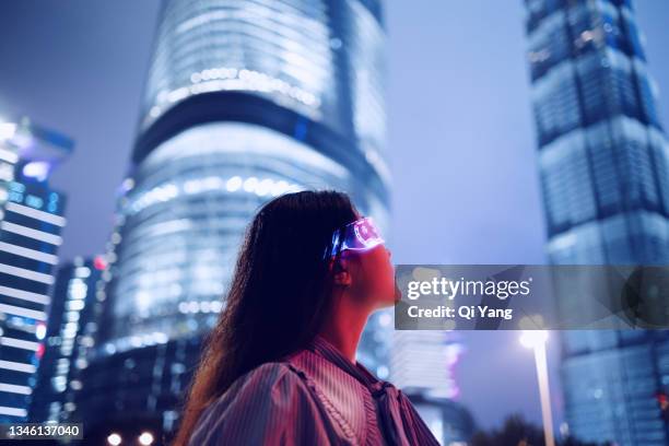 young businesswoman standing against contemporary financial skyscrapers in the downtown financial district - angeleuchtet zahlen mensch stock-fotos und bilder