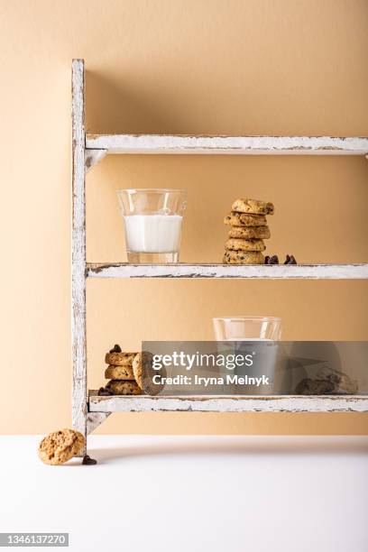 stack of gluten free chocolate chip cookies with glass of plant milk over beige orange background. - henkelkrug stock-fotos und bilder